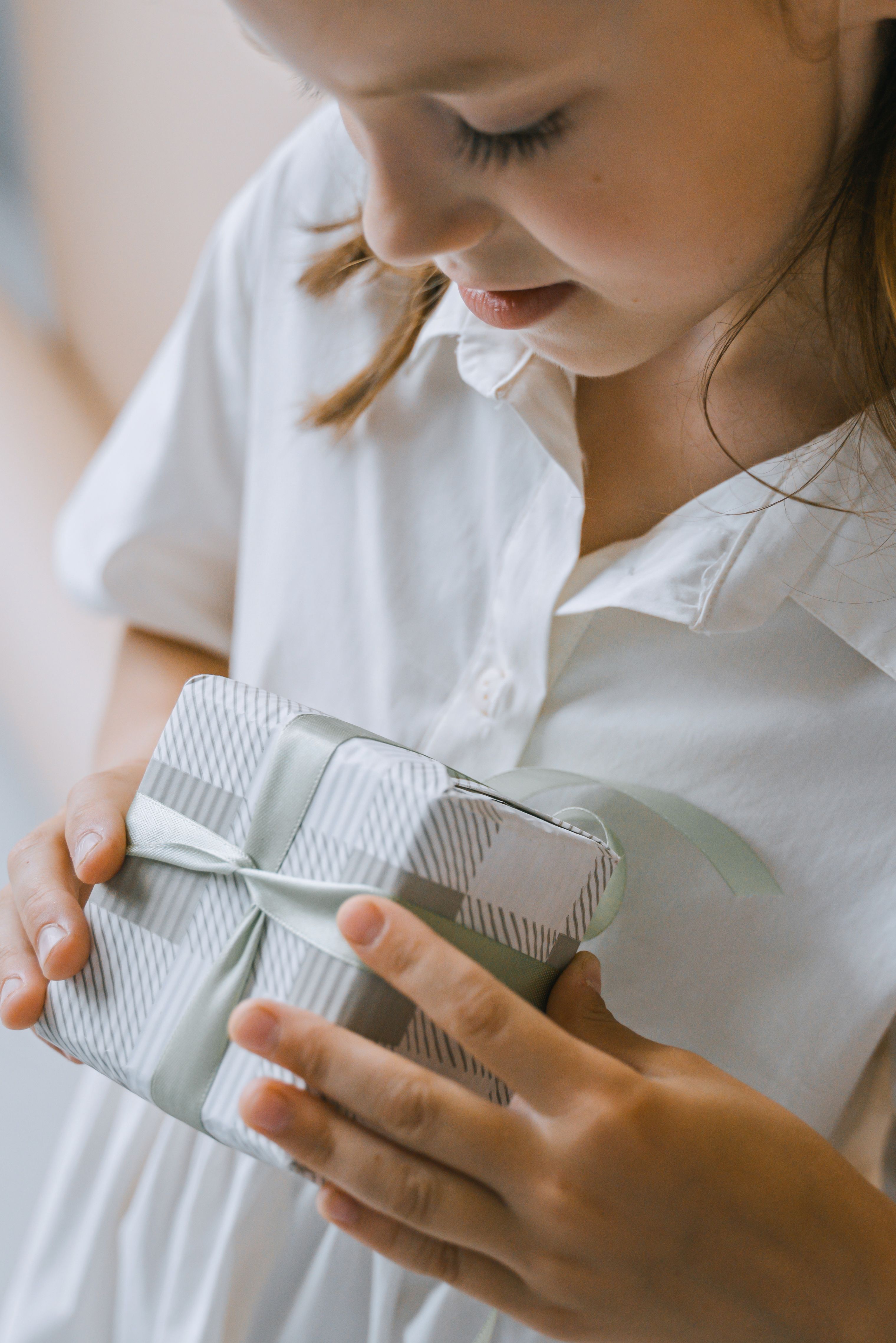 Young girl looking down at a carefully wrapped gift