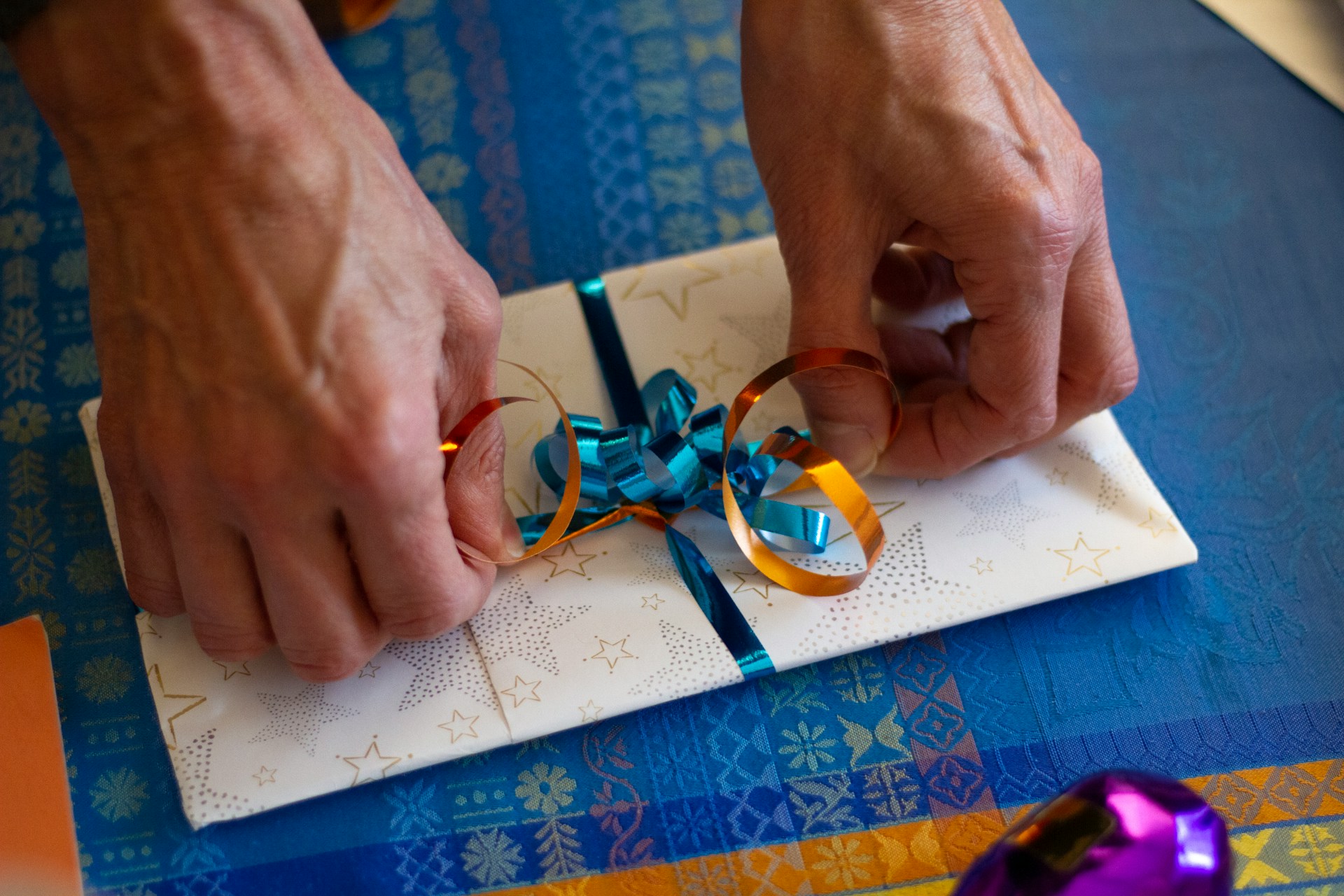 Hands carefully tying colorful ribbons on a wrapped gift